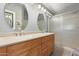 Bathroom featuring a double sink vanity, stylish mirrors, lighting fixtures, and a glass-enclosed shower at 21181 N 80Th Ln, Peoria, AZ 85382