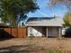 View of small home with a wooden fence and a yard with trees, under a clear blue sky at 2206 N 11Th St, Phoenix, AZ 85006