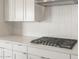 A modern gas cooktop sits on a quartz countertop with bright white backsplash and cabinets at 22660 E Pegasus Pkwy, Queen Creek, AZ 85142