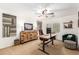 This home office has decor art, a ceiling fan, a wooden cabinet, a comfortable green chair and an ottoman at 24916 N 80Th Ln, Peoria, AZ 85383