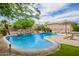 Beautiful pool with lush landscaping, waterfall feature, and patio furniture at 24916 N 80Th Ln, Peoria, AZ 85383