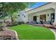 Backyard with lush green lawn, stone columns, and a covered outdoor seating area at 2527 E Beechnut Ct, Chandler, AZ 85249