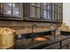 Close-up of bar with copper sink, dark cabinets, granite countertop, and decorative backsplash adding luxury and style at 2527 E Beechnut Ct, Chandler, AZ 85249