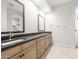 Bright bathroom with a double sink vanity, black countertop, and two decorative mirrors at 26139 S 225Th Way, Queen Creek, AZ 85142