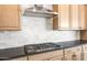 Close-up of kitchen gas cooktop with light wood cabinets and backsplash at 26139 S 225Th Way, Queen Creek, AZ 85142