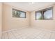 This bedroom features tiled floors, beige walls, and natural light from its two windows at 3013 W Port Au Prince Ln, Phoenix, AZ 85053