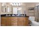 Bathroom with double sinks, wood cabinets, and black granite countertops at 3021 S Evergreen Rd, Tempe, AZ 85282