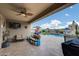 Outdoor patio with tan couches, a mounted tv, and a beautiful view of the backyard pool at 3515 N Brooklyn Dr, Buckeye, AZ 85396