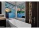 Modern bathroom with a luxurious soaking tub positioned under a large window with a scenic view of the colorful sunset at 37221 N Holiday Ln, Carefree, AZ 85377