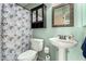 Cozy bathroom featuring a pedestal sink, toilet, and leaf-patterned shower curtain at 4117 W Whispering Wind Dr, Glendale, AZ 85310