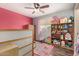 Bright bedroom with Minnie Mouse rug, ceiling fan, and well-organized bookshelf at 4117 W Whispering Wind Dr, Glendale, AZ 85310
