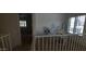 Hallway with white railing overlooks lower room with a desk, with view to another room with plantation shutters at 475 S Seawynds Blvd, Gilbert, AZ 85233
