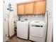 A bright laundry room with white washer and dryer, upper cabinets, and an ironing board at 4970 S Desert Willow Dr, Gold Canyon, AZ 85118