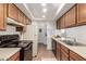 Efficient kitchen featuring wood cabinets, black appliances, and in-unit laundry access at 520 N Stapley Dr # 253, Mesa, AZ 85203