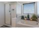 Bright bathroom with a glass-enclosed shower, soaking tub and a window with a view at 5239 W Leodra Ln, Laveen, AZ 85339