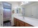 Bright bathroom featuring a vanity with warm wood cabinetry and framed mirrors above a white countertop and integrated sink at 5239 W Leodra Ln, Laveen, AZ 85339