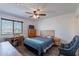 Well-lit bedroom featuring a bed with a wooden headboard, a ceiling fan, and a desk beneath a window at 5239 W Leodra Ln, Laveen, AZ 85339