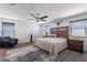 Relaxing main bedroom features a ceiling fan, comfortable chair and gray wood-look floors at 5239 W Leodra Ln, Laveen, AZ 85339