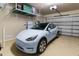 Spacious garage featuring a Tesla Model Y, energy storage, and overhead storage racks at 5649 E Desert Forest Trl, Cave Creek, AZ 85331