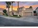 Elegant home featuring desert landscaping, a three-car garage, and mature palm trees at 633 W Aster Ct, Chandler, AZ 85248