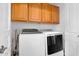 A bright laundry room with wooden cabinets and modern white appliances at 633 W Aster Ct, Chandler, AZ 85248