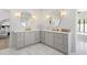 Bright bathroom with dual vanity, white quartz countertops and grey shaker cabinets, complemented by stylish sconces and oval mirrors at 6701 E San Miguel Ave, Paradise Valley, AZ 85253