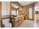 Well-lit bathroom featuring a double vanity, a framed mirror, wooden cabinets, and shuttered windows at 13249 E Summit Dr, Scottsdale, AZ 85259