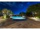 Stunning pool with a waterfall, surrounded by lush landscaping and a brick paver deck at twilight at 13249 E Summit Dr, Scottsdale, AZ 85259