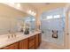 Bathroom with dual sinks, wood cabinets, an enclosed shower, and neutral tile flooring at 15353 W Cheery Lynn Rd, Goodyear, AZ 85395