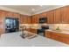 Spacious kitchen features warm wood cabinetry, modern black appliances, and a center island with stone countertop at 15353 W Cheery Lynn Rd, Goodyear, AZ 85395