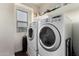 Efficient laundry room with modern washer and dryer, shelving, and a window, designed for convenience at 1647 W Gold Mine Way, San Tan Valley, AZ 85144