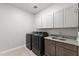 Well-lit laundry room boasting sleek washer and dryer, upper cabinets and granite countertop sink at 18387 W Mountain Sky Ave, Goodyear, AZ 85338