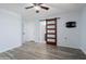 Open bedroom leading to bathroom with sliding wood door, wood floors and neutral walls at 2717 N 107Th Dr, Avondale, AZ 85392