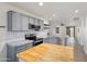 Modern kitchen featuring gray cabinets, stainless steel appliances, a kitchen island with a butcher block top and a tiled backsplash at 2717 N 107Th Dr, Avondale, AZ 85392