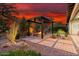 Backyard fire pit with an overhead pergola, surrounded by desert landscaping and a stunning sunset at 29344 N 132Nd Ln, Peoria, AZ 85383
