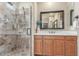 Bathroom featuring tiled glass-door shower stall, wood cabinets, and framed mirror at 3613 W Plymouth Dr, Anthem, AZ 85086
