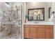 Bathroom showcasing a walk-in shower with custom tile work, a glass door, and a vanity with a framed mirror at 3613 W Plymouth Dr, Anthem, AZ 85086