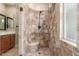 Close up of stone tiled shower with bench, bronze hardware, and glass door at 3613 W Plymouth Dr, Anthem, AZ 85086