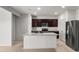 Well-lit kitchen featuring stainless steel appliances, granite countertops, dark wood cabinets, and a functional center island at 42885 W Vincent Dr, Maricopa, AZ 85138