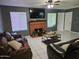 Spacious living room with a brick fireplace, comfortable leather seating, and plenty of natural light from the windows at 4507 E Saint Catherine Ave, Phoenix, AZ 85042