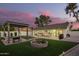 Expansive backyard featuring lush lawn, dining area, modern pergola, and custom fire pit at 5238 E Beck Ln, Scottsdale, AZ 85254