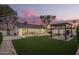 A sprawling backyard features green lawn, patio, pergola, and modern exterior lighting at 5238 E Beck Ln, Scottsdale, AZ 85254