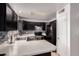 Well-lit kitchen features black cabinets, stainless steel appliances, and stylish backsplash, offering modern charm at 6038 W Gelding Dr, Glendale, AZ 85306