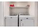 Functional laundry area features a convenient shelf and modern, full-sized appliances at 6038 W Gelding Dr, Glendale, AZ 85306