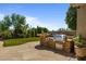 Outdoor kitchen with stone barbecue, stone countertops, lush landscaping, and a blue sky at 6621 E Oberlin Way, Scottsdale, AZ 85266