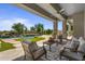 Inviting covered patio area with a stone fireplace, luxurious seating, and a stunning pool view for outdoor relaxation at 6621 E Oberlin Way, Scottsdale, AZ 85266