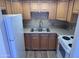 Galley kitchen featuring stainless sink, wood cabinetry, appliances, and tile floors at 700 W University Dr # 203, Tempe, AZ 85281