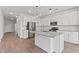 Bright kitchen features white cabinetry, stainless steel appliances, a large island, and wood-look tile floors at 7420 S 76Th Ln, Laveen, AZ 85339