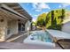 Private backyard featuring a covered patio, mature trees, brick pavers, and a relaxing hot tub at 8405 E San Pedro Dr, Scottsdale, AZ 85258