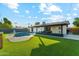 Beautiful backyard with a large pool, a covered patio and synthetic grass at 8701 E Sage Dr, Scottsdale, AZ 85250